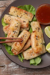 Photo of Tasty fried spring rolls served on wooden table, top view