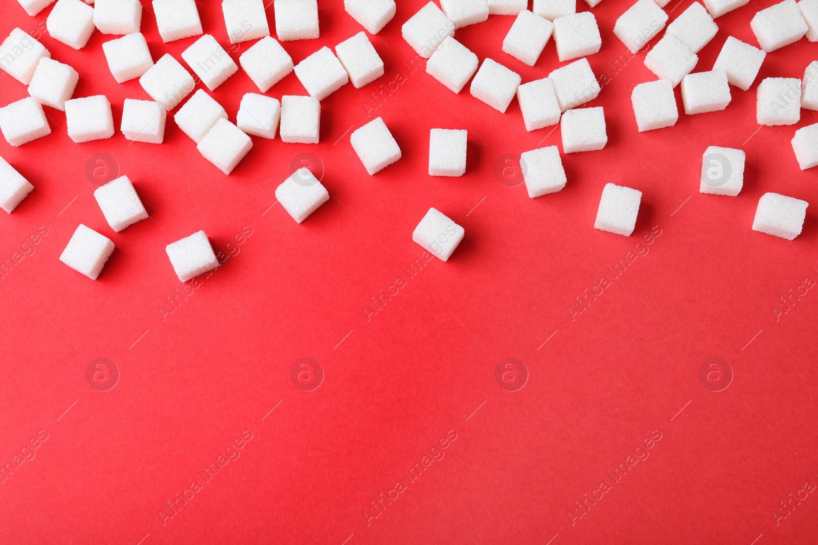 Photo of Refined sugar cubes on red background, top view. Space for text
