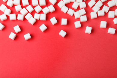 Refined sugar cubes on red background, top view. Space for text