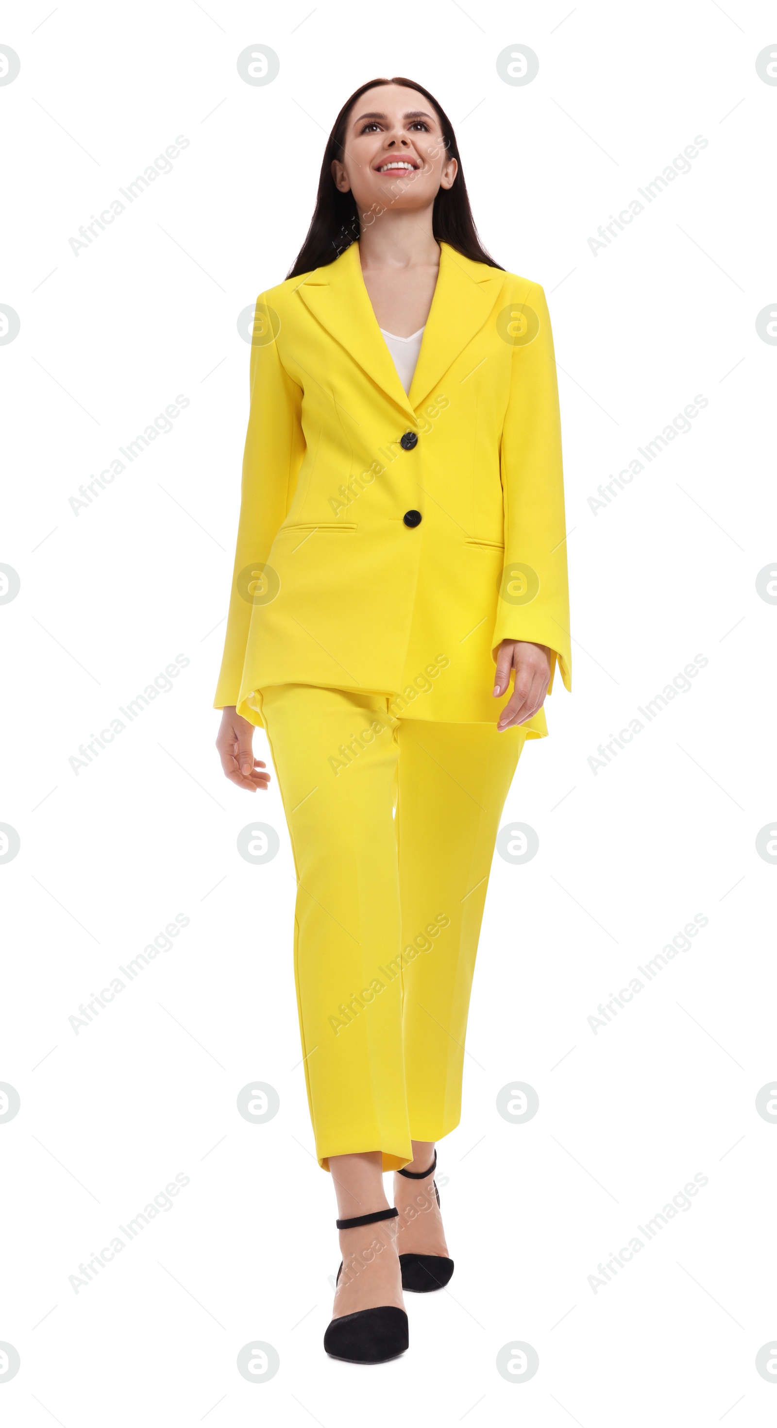 Photo of Beautiful businesswoman in yellow suit walking on white background, low angle view