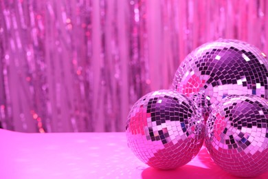 Shiny disco balls on blurred background, toned in pink. Space for text