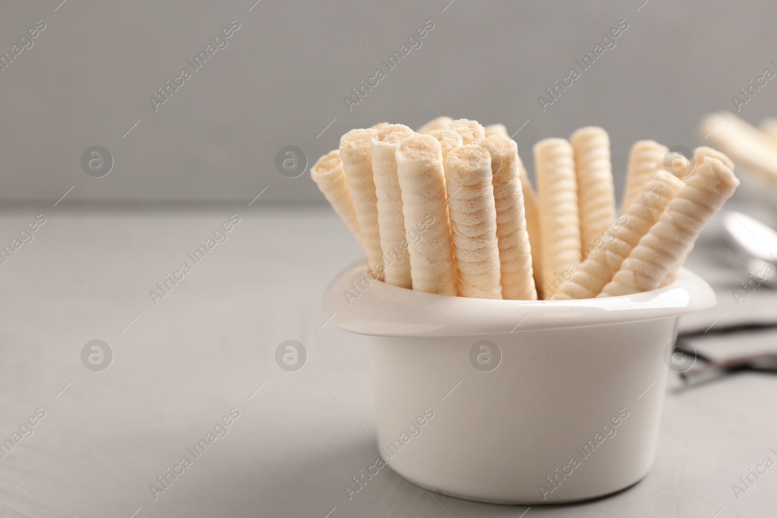 Photo of Bowl with delicious vanilla wafer rolls on table, space for text. Sweet food