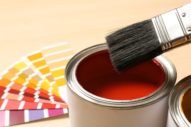 Red paint can, brush and color palette on table, closeup. Space for text