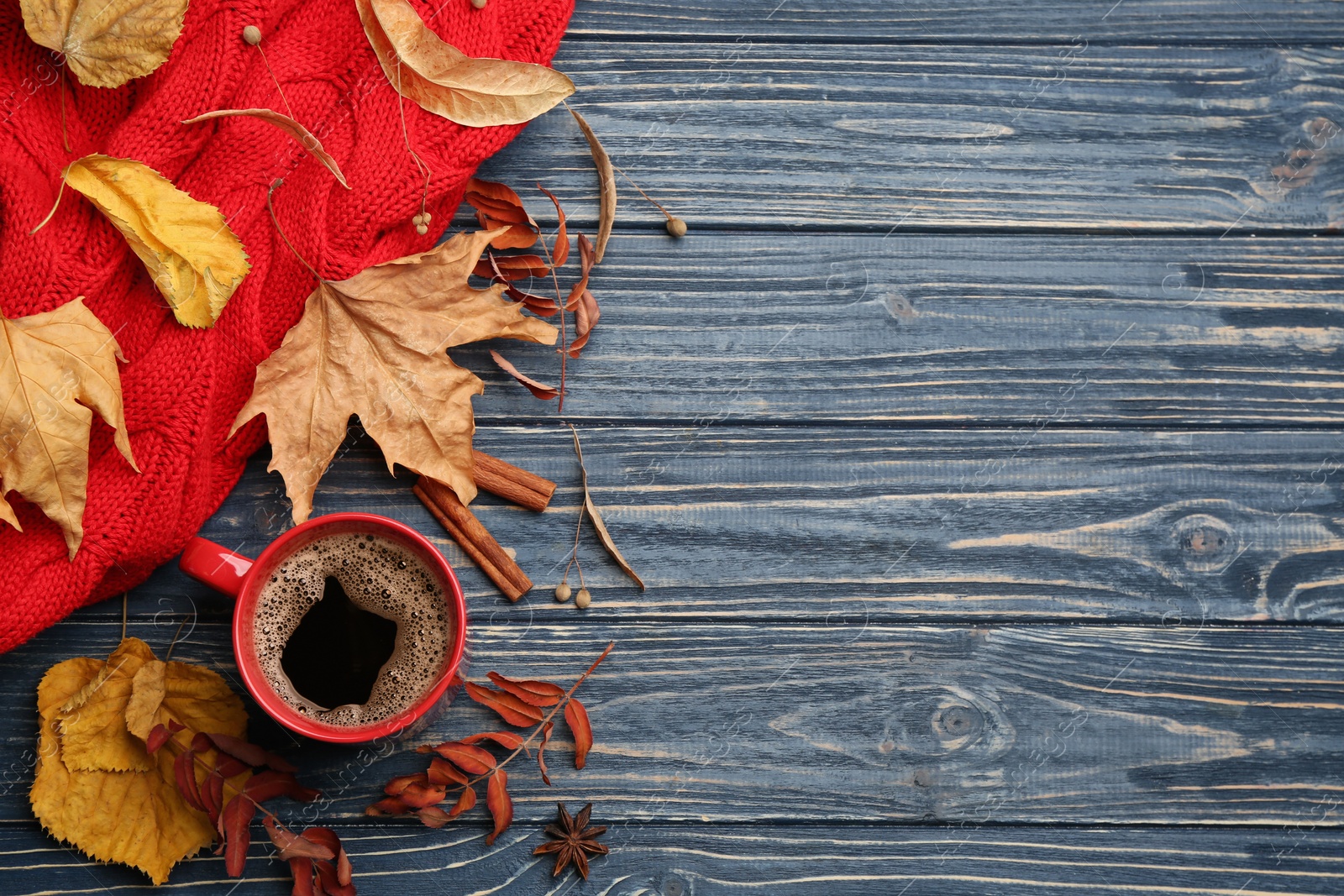 Photo of Flat lay composition with cup of hot drink and autumn leaves on blue wooden table, space for text. Cozy atmosphere
