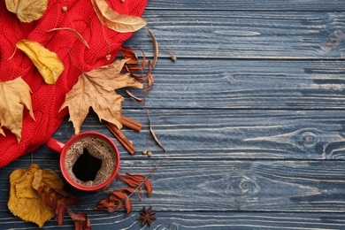 Flat lay composition with cup of hot drink and autumn leaves on blue wooden table, space for text. Cozy atmosphere
