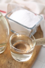 Photo of Vinegar in glass saucepan and baking soda on table