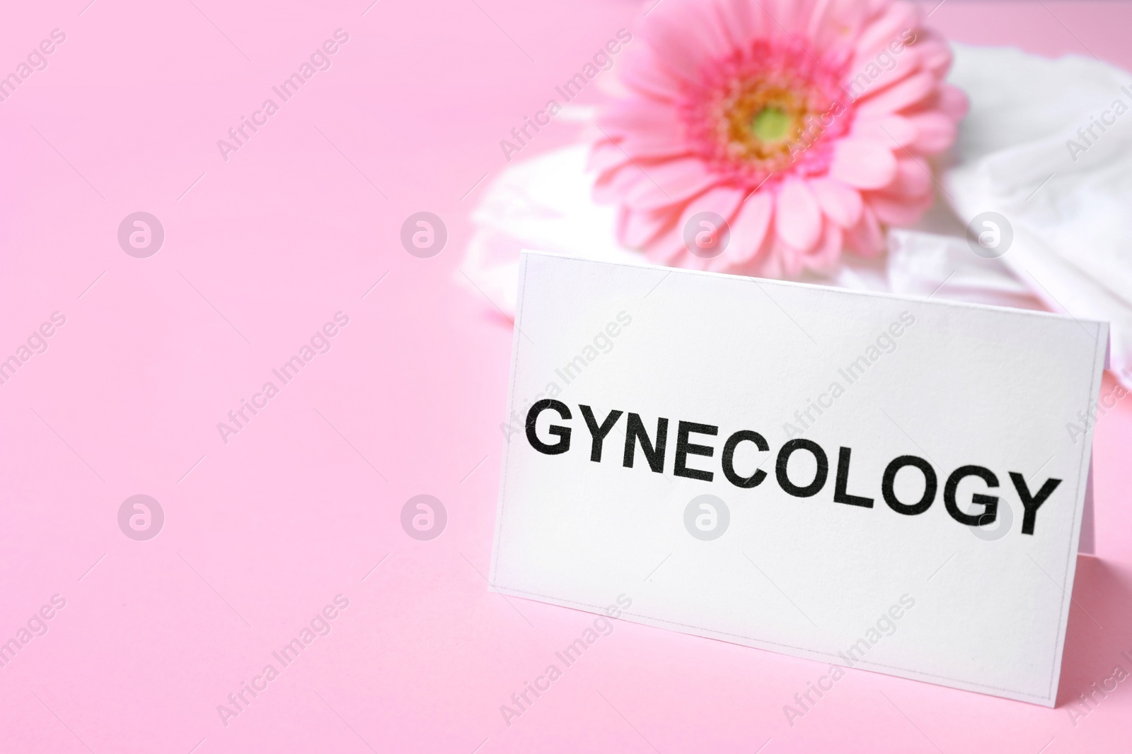 Photo of Card with word Gynecology, packed menstrual pads and flower on color background. Space for text