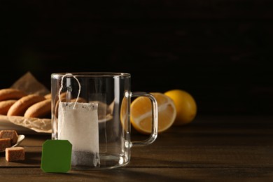 Photo of Tea bag in empty glass cup on dark wooden table. Space for text