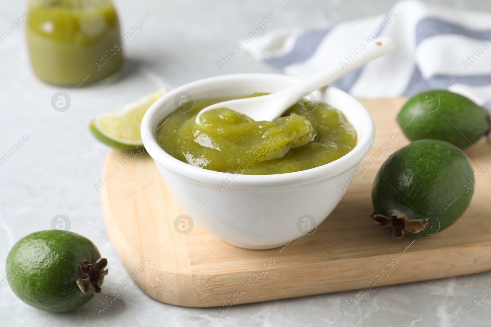 Photo of Feijoa jam and fresh fruits on light grey marble table