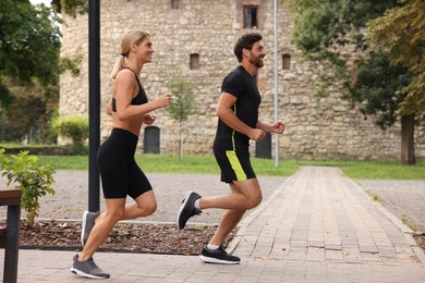 Healthy lifestyle. Happy couple running in park, space for text