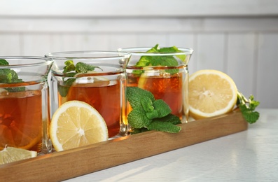 Photo of Wooden tray with hot tea in glasses on table, closeup