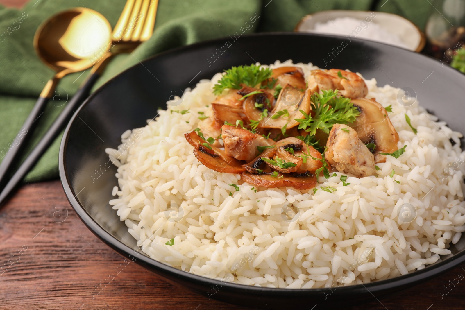 Photo of Delicious rice with mushrooms and parsley on wooden table, closeup