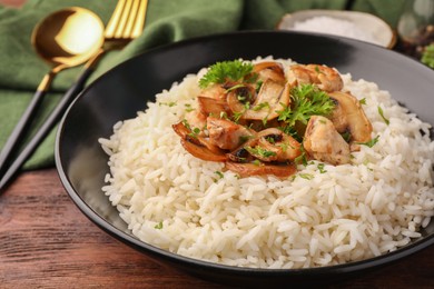 Photo of Delicious rice with mushrooms and parsley on wooden table, closeup