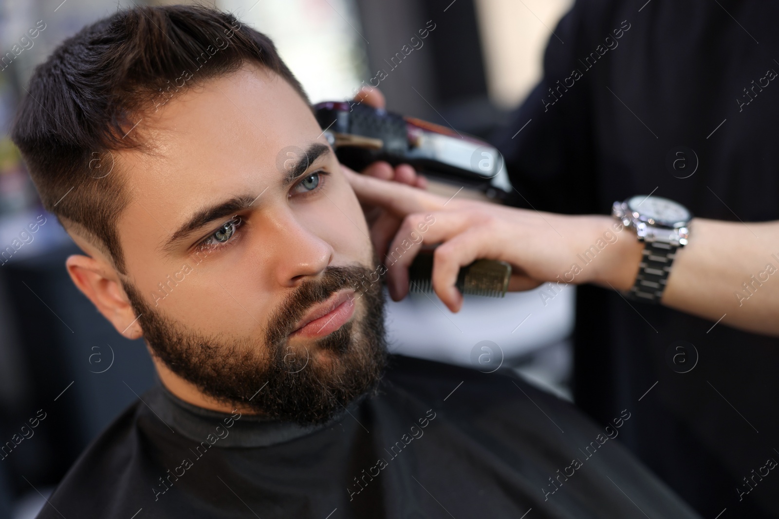 Photo of Professional hairdresser working with client in barbershop