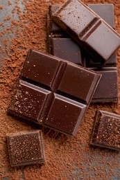 Delicious dark chocolate and cocoa powder on grey table, flat lay