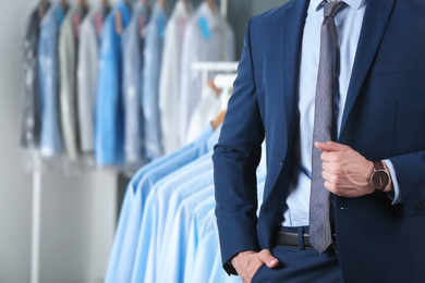 Image of Businessman and rack with clean clothes at dry-cleaner's, closeup. Space for text 