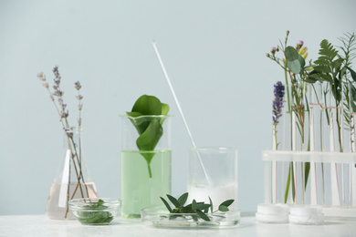 Photo of Herbal cosmetic products, laboratory glassware and ingredients on white table