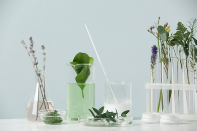 Herbal cosmetic products, laboratory glassware and ingredients on white table