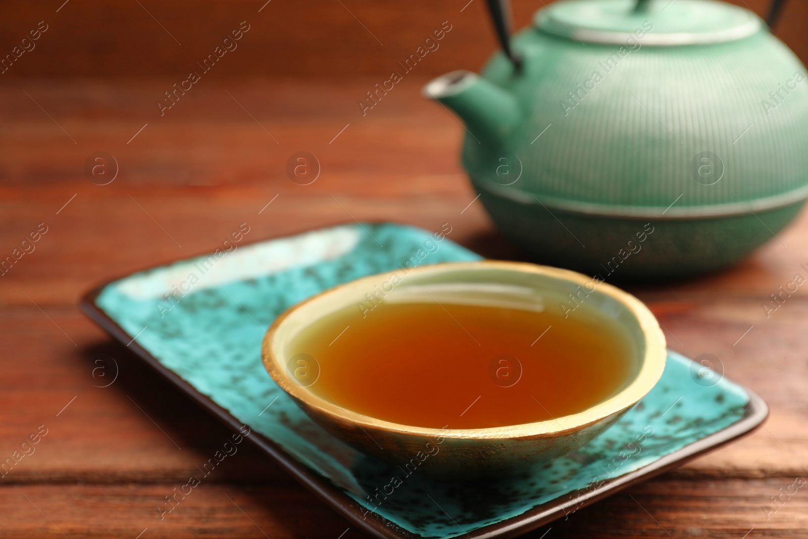 Photo of Teapot and cup of freshly brewed tea on wooden table, closeup. Traditional ceremony