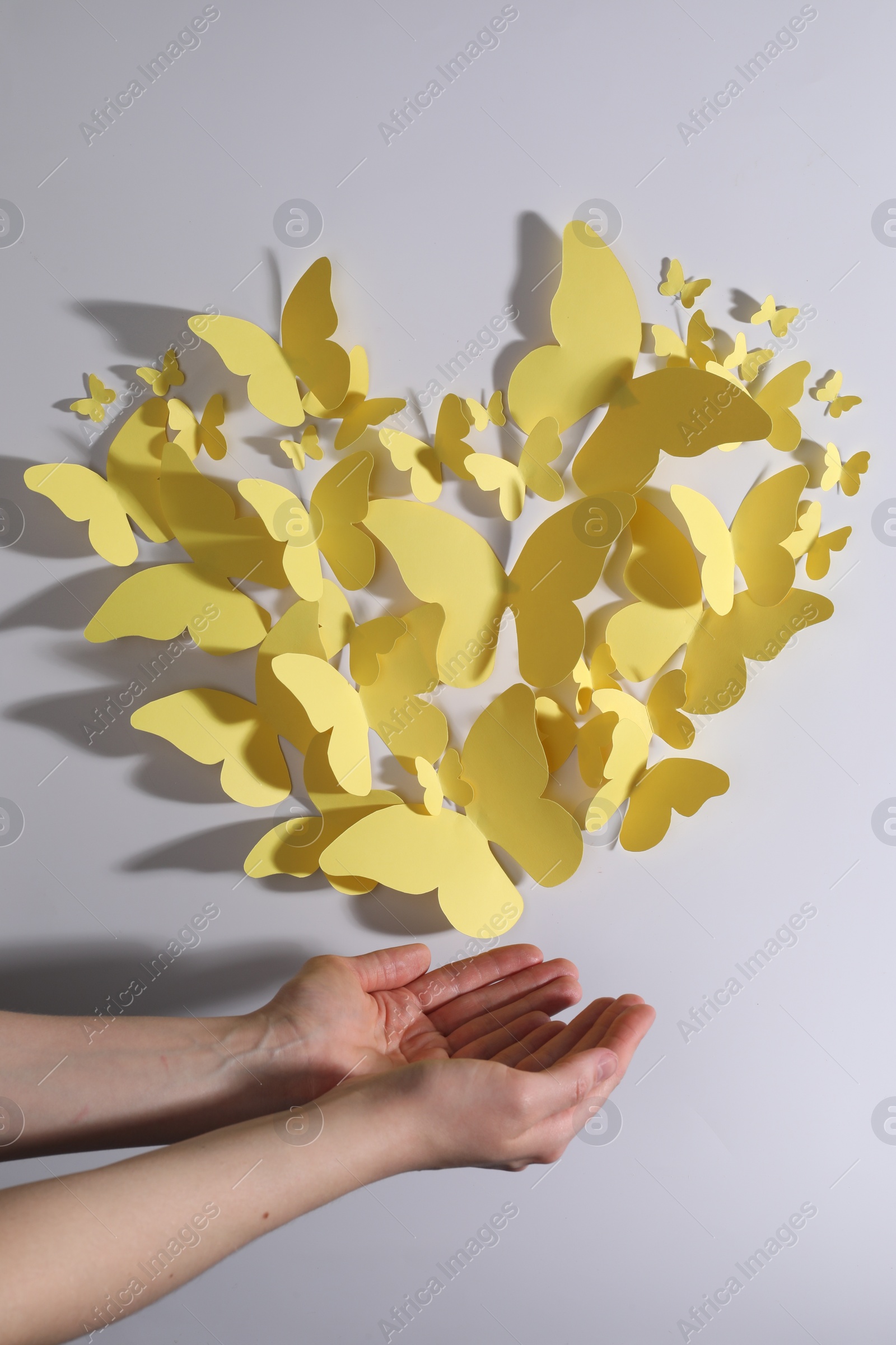 Photo of Woman with yellow paper butterflies on white background, top view