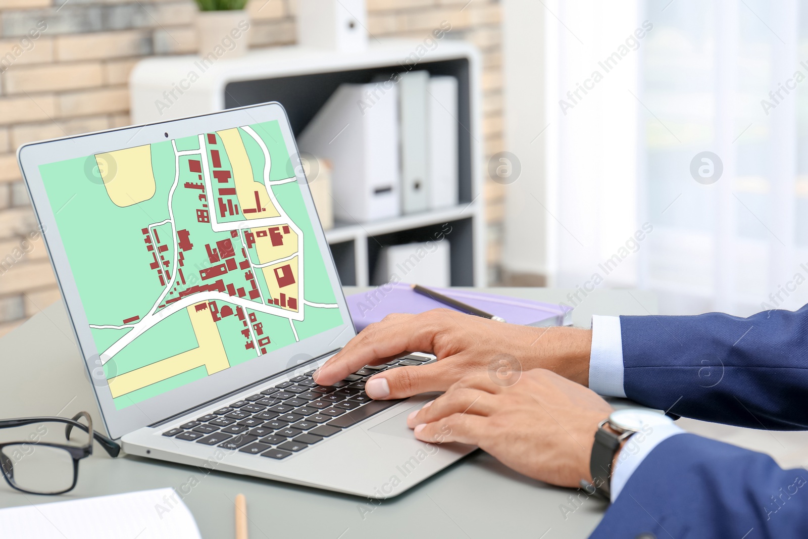 Image of Man analyzing cadastral map on laptop at table, closeup 