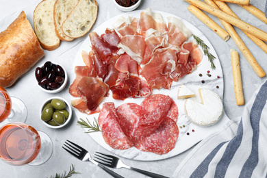 Photo of Tasty prosciutto served on light grey marble table, flat lay