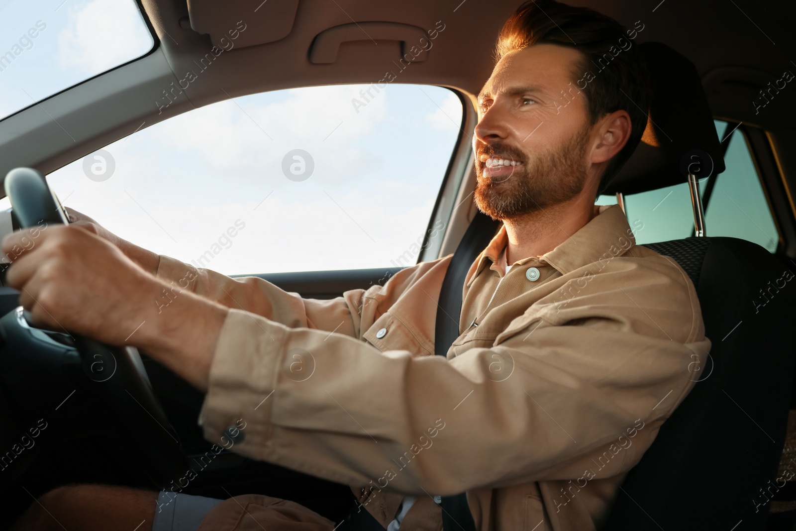 Photo of Happy man sitting in his car, low angle view. Enjoying trip