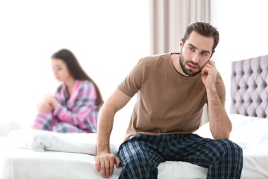 Photo of Young couple ignoring each other after having argument in bedroom