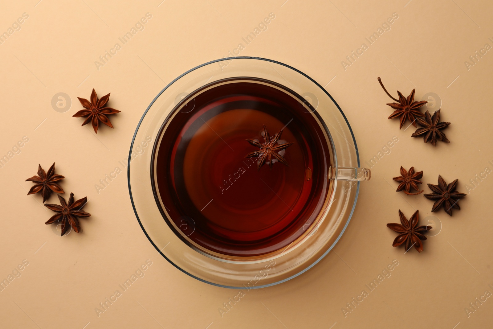 Photo of Cup of tea and anise stars on beige background, flat lay