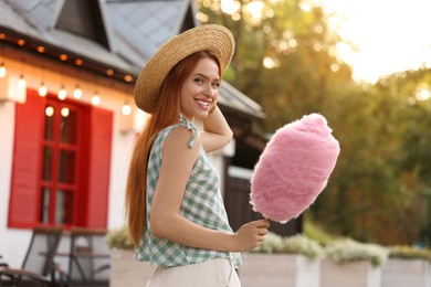 Smiling woman with cotton candy outdoors on sunny day