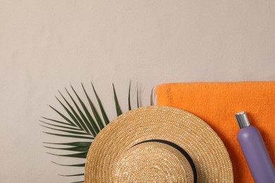 Photo of Beach towel, hat, sunscreen and palm leaf on sand, flat lay. Space for text