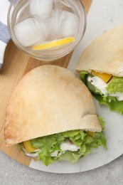 Photo of Delicious pita sandwiches with chicken breast and vegetables on light gray table, flat lay