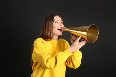 Young woman with megaphone on black background