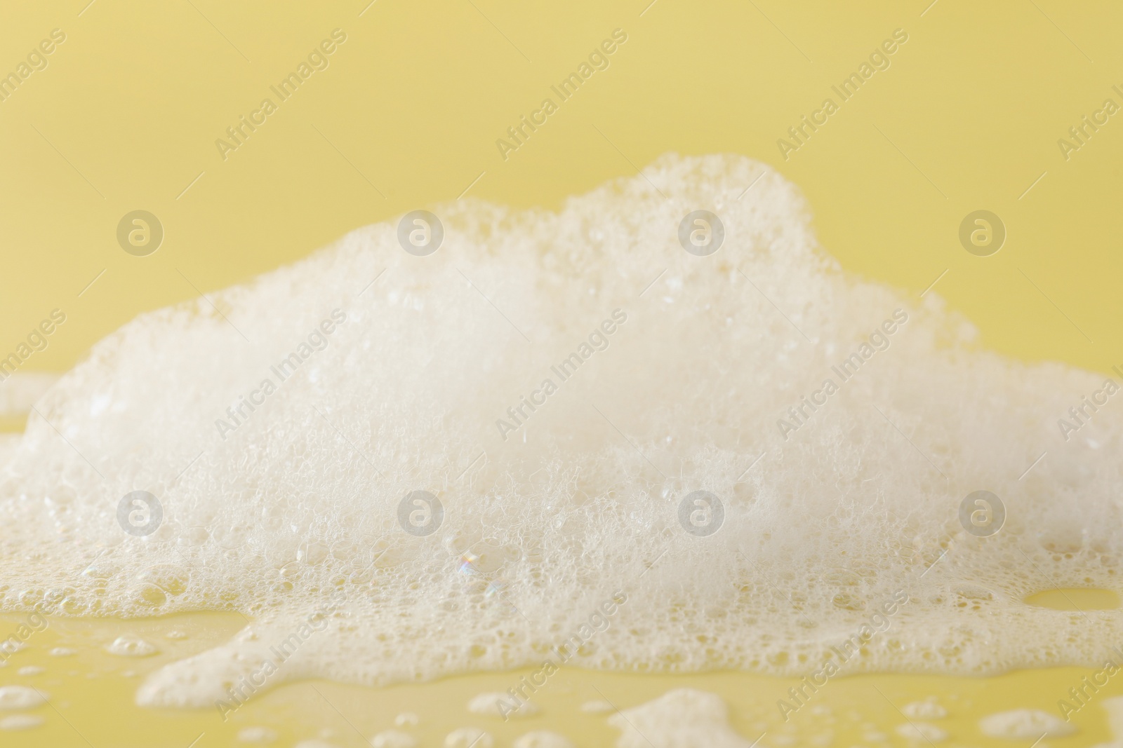 Photo of Fluffy bath foam on pale orange background, closeup