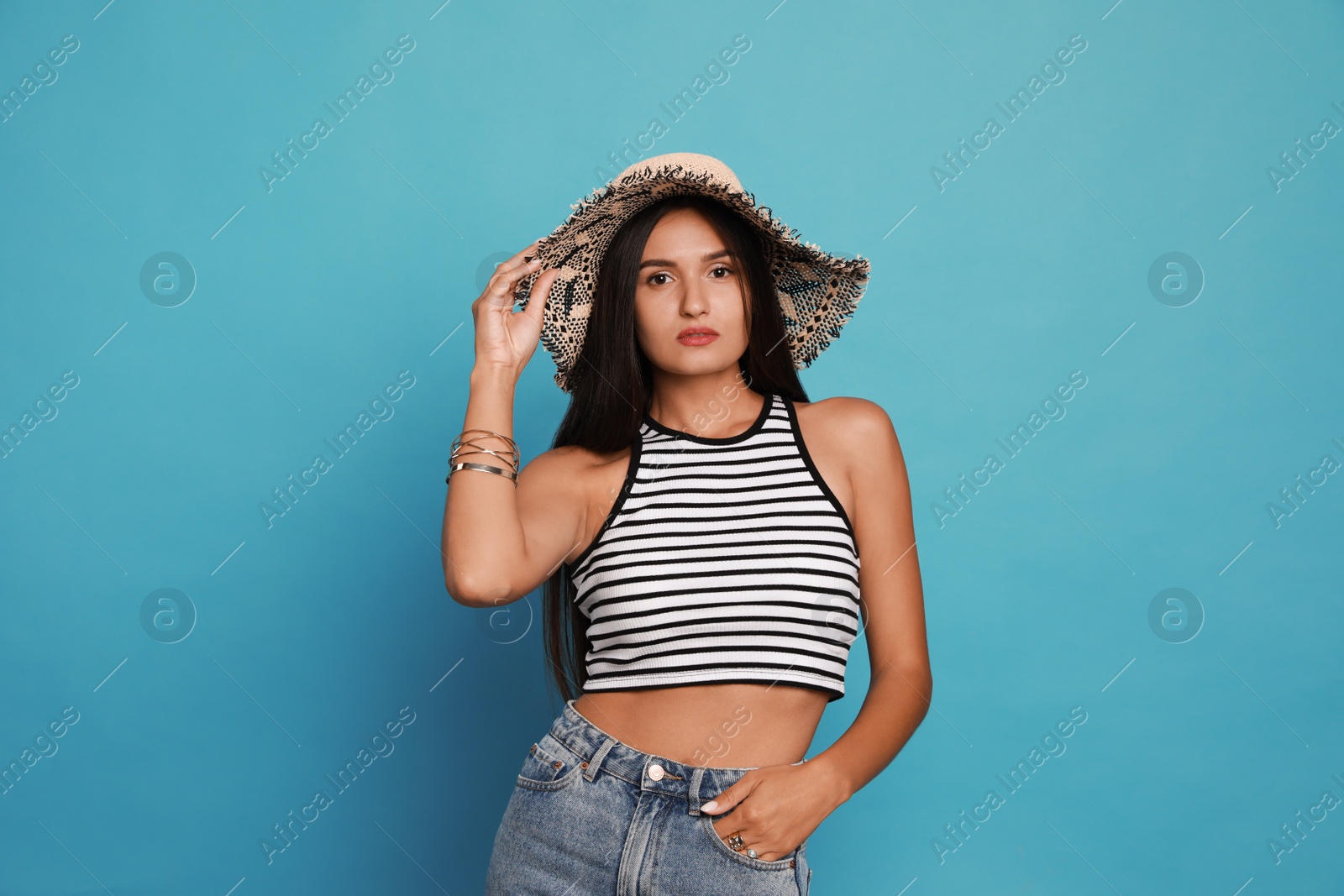 Photo of Beautiful young woman with straw hat on light blue background