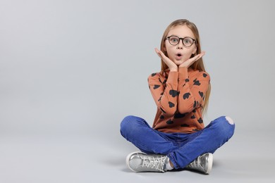 Emotional girl in glasses on light grey background. Space for text