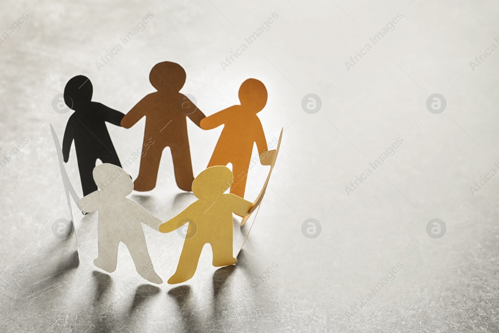 Photo of Paper people holding hands on light background. Unity concept