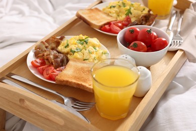 Photo of Good morning. Tray with tasty breakfast on bed
