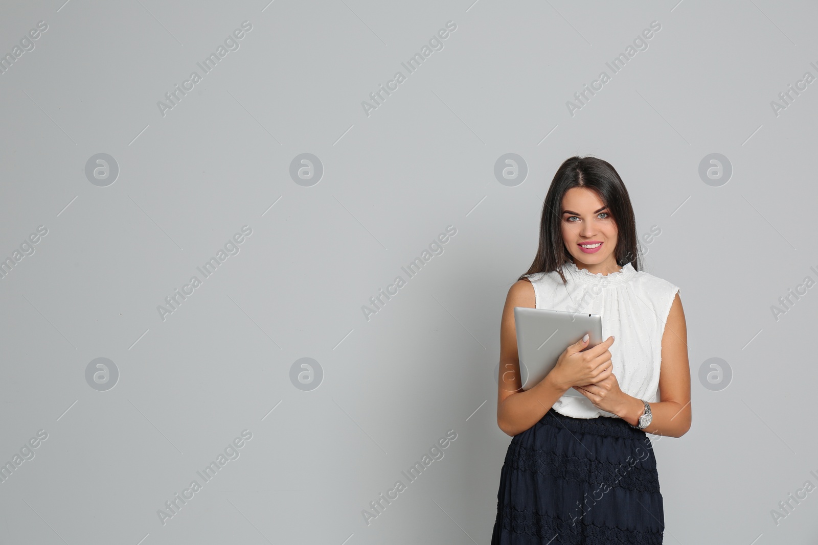 Photo of Beautiful woman with tablet wearing office clothes against gray background. Space for text