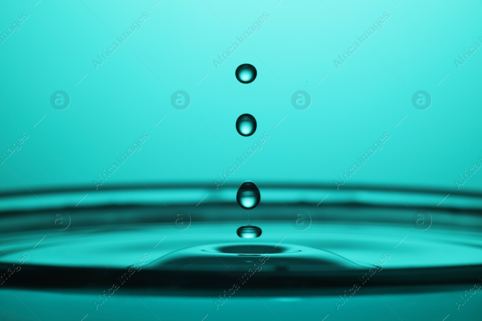 Photo of Splash of clear water with drops on turquoise background, closeup