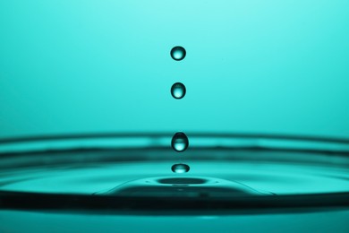 Splash of clear water with drops on turquoise background, closeup
