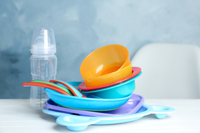Photo of Set of plastic dishware on white table. Serving baby food