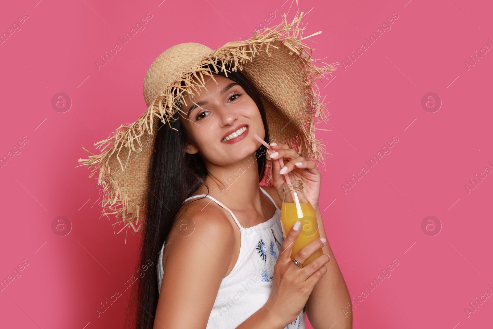 Photo of Beautiful young woman with straw hat and bottle of refreshing drink on pink background