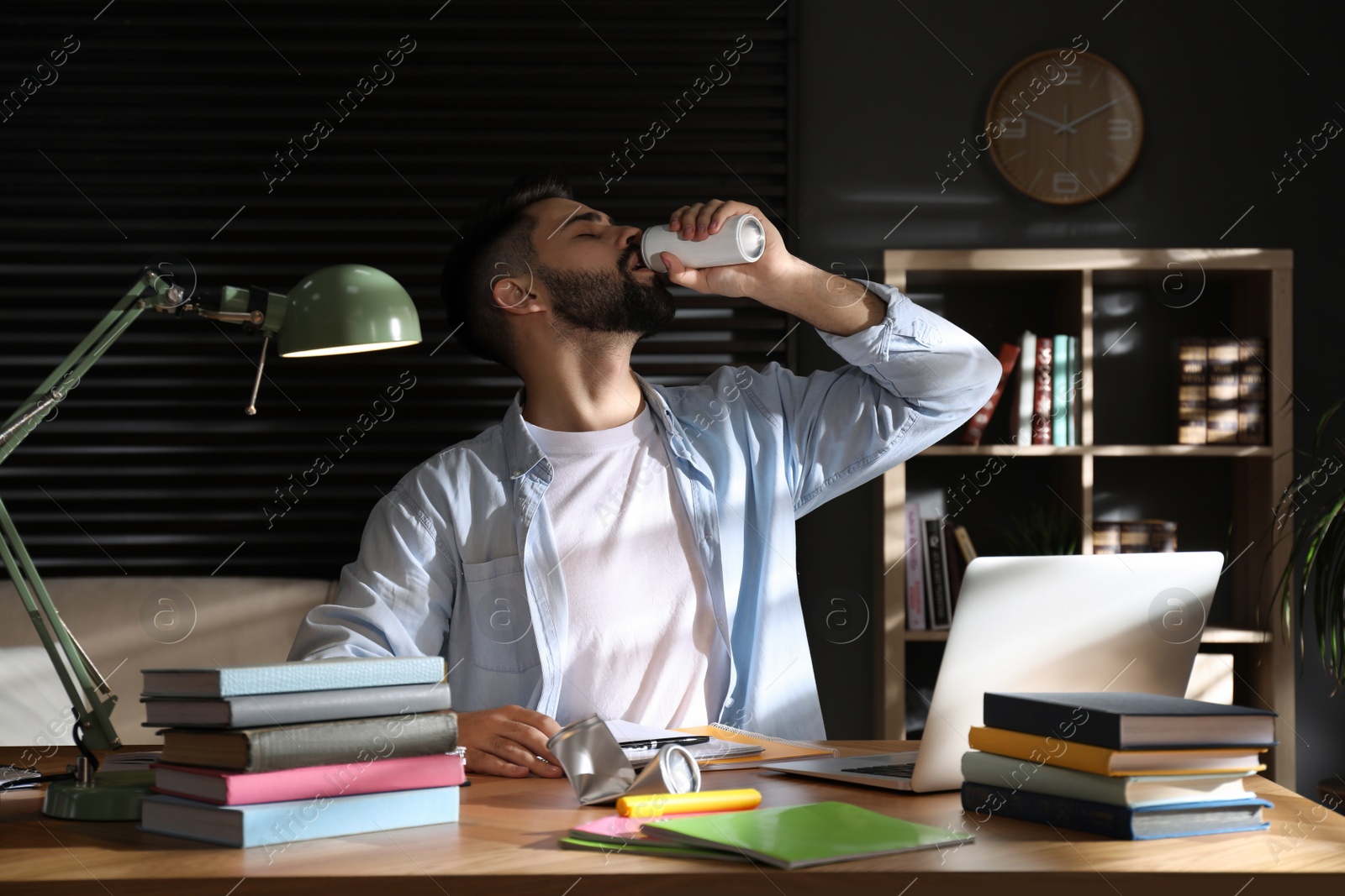 Photo of Young man with energy drink studying at home