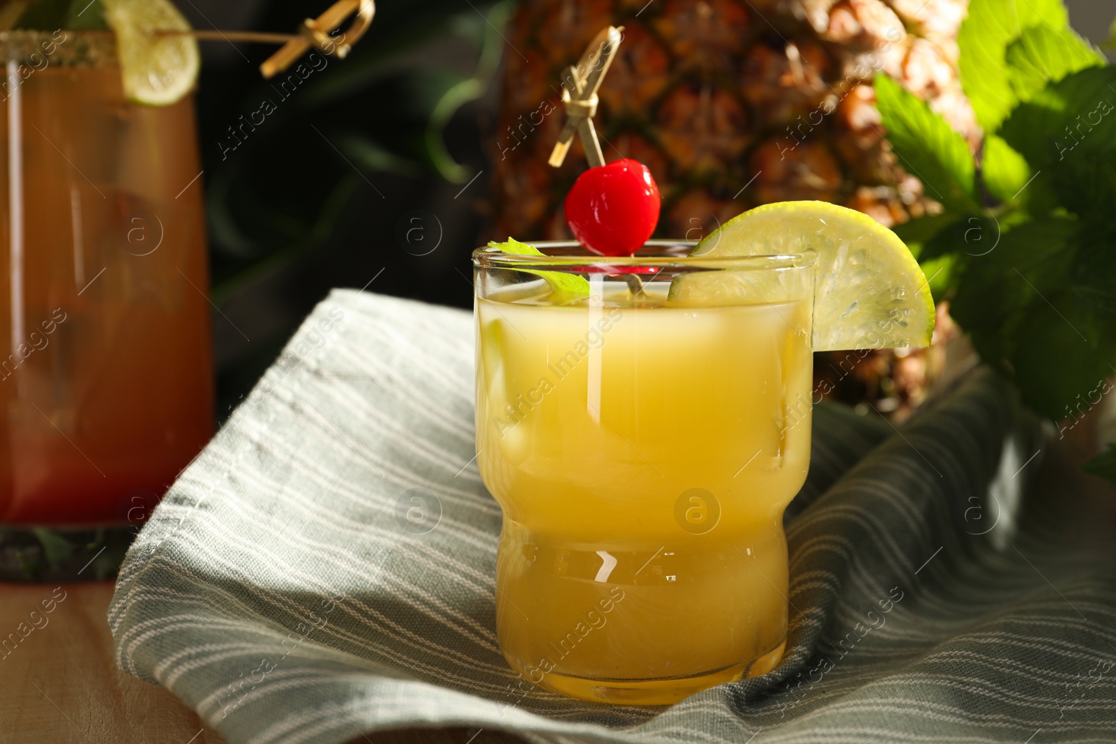 Photo of Tasty pineapple cocktail with cherry and lime on table, closeup
