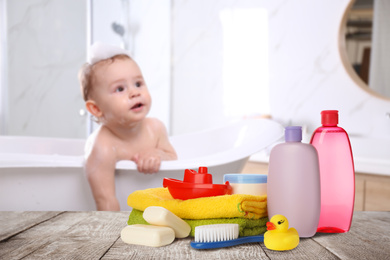 Image of Baby cosmetic products, toys and towels on table in bathroom