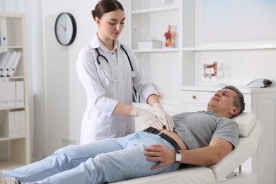 Photo of Gastroenterologist examining patient with stomach pain on couch in clinic