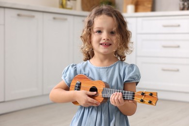 Little girl playing toy guitar in kitchen