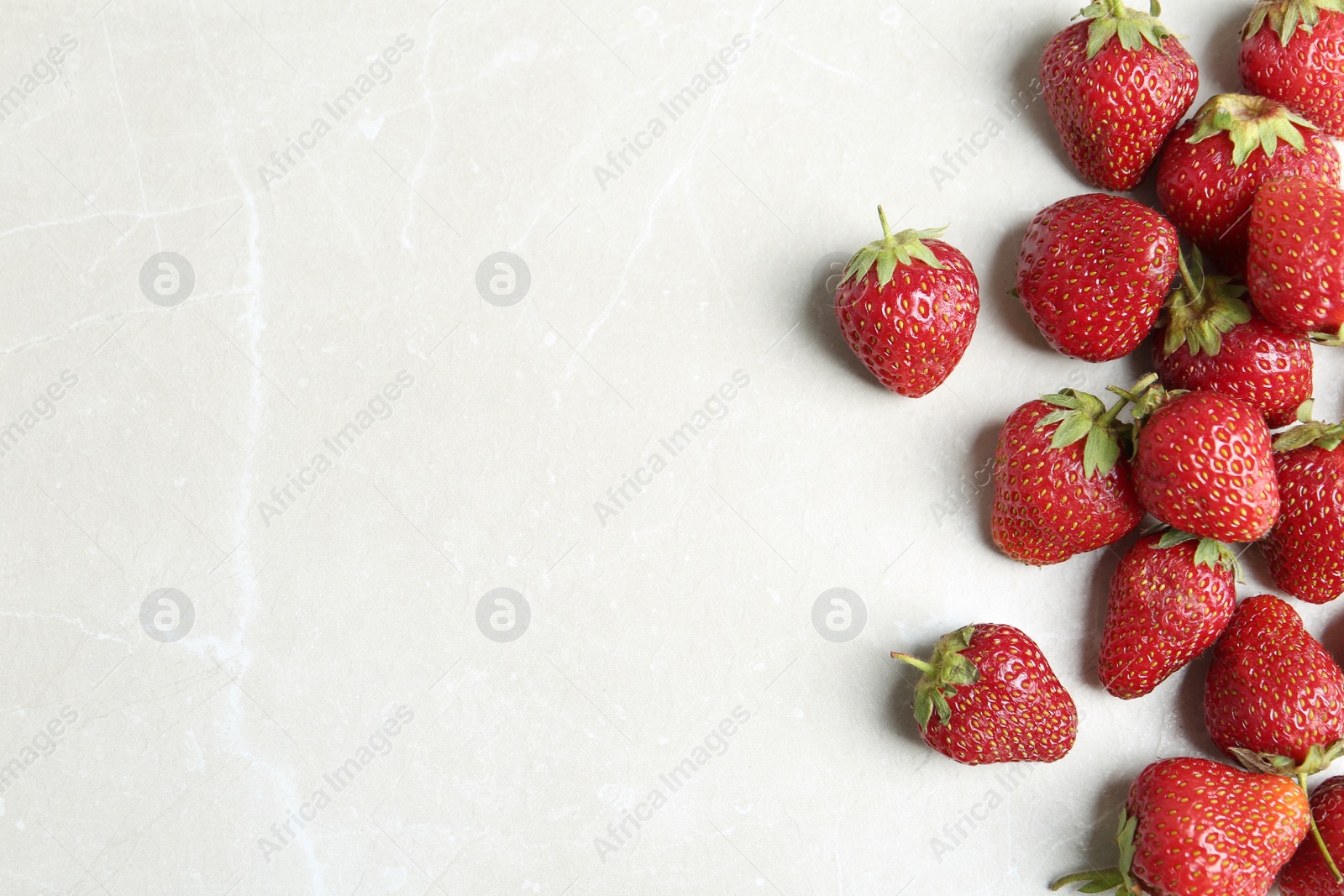 Photo of Delicious ripe strawberries on light grey marble table, flat lay. Space for text