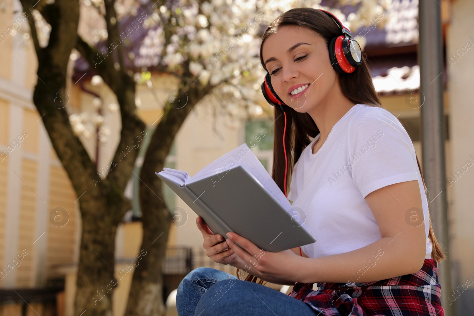 Photo of Happy young woman reading book in park